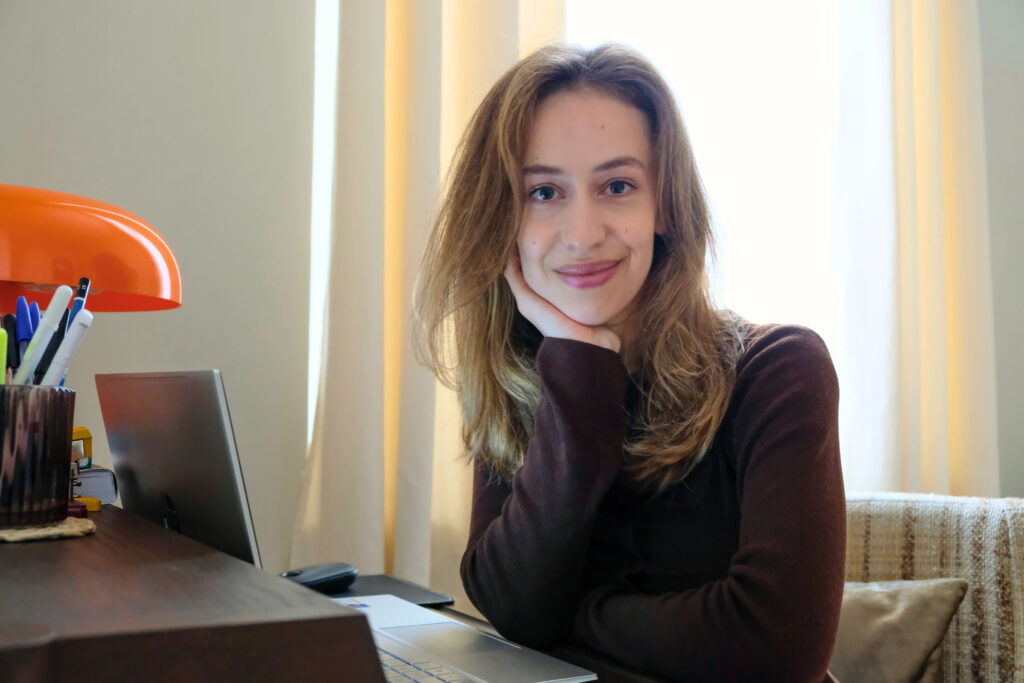 Freelance redacteur lacht in camera zittend aan bureau met laptop voor zich