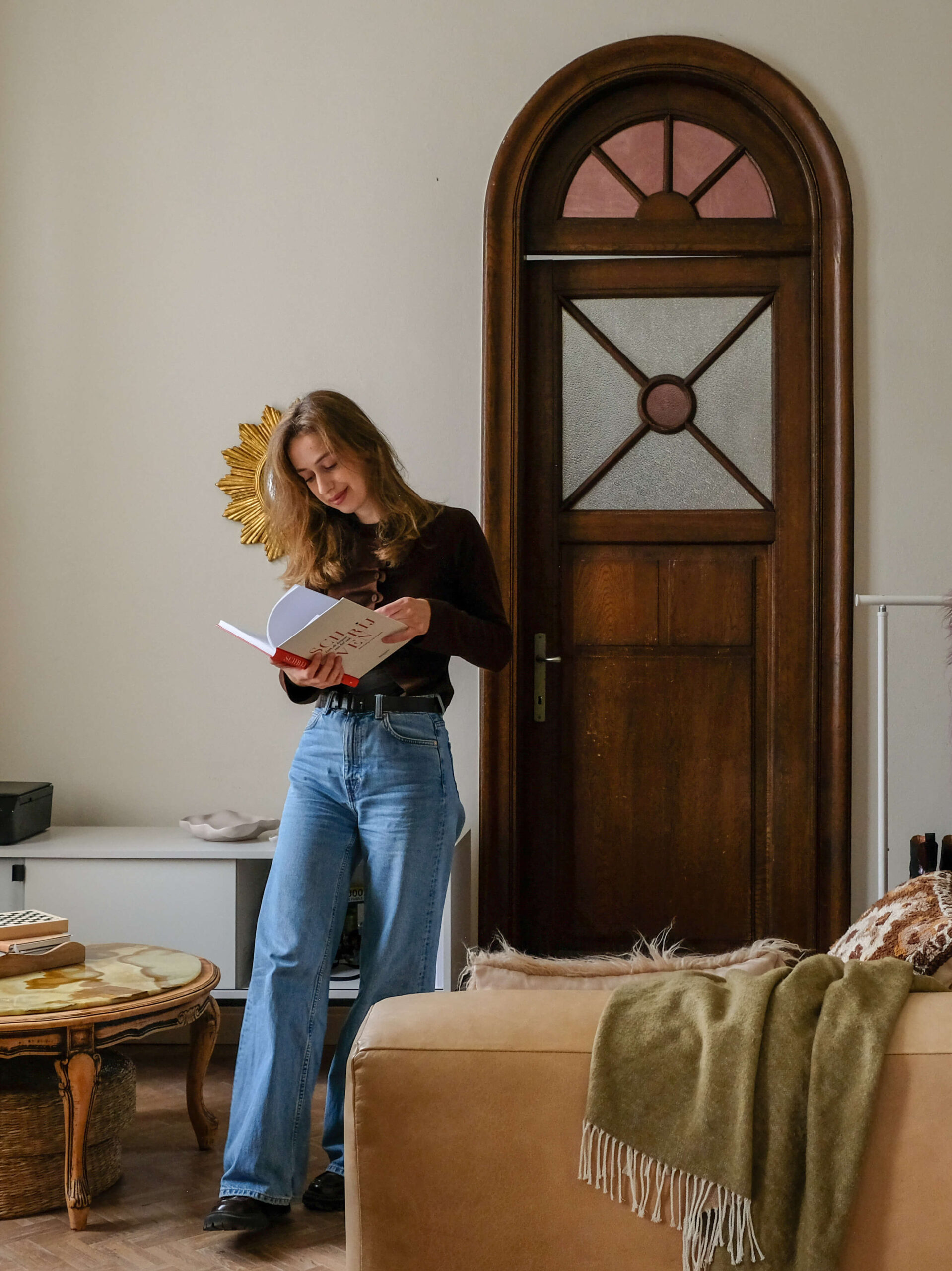 Freelance copywriter wandelt door gezellige woonkamer met boek